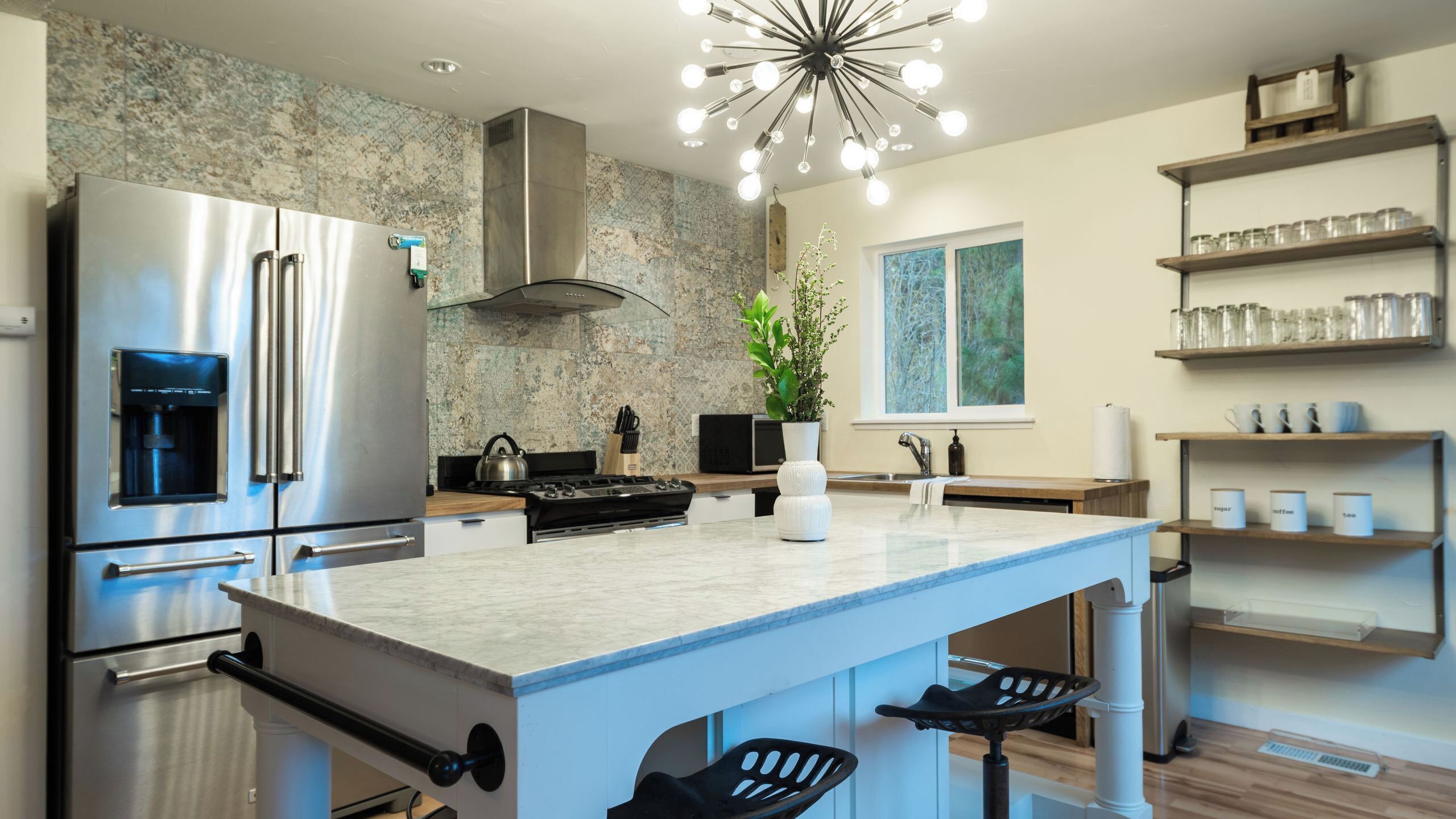 Een moderne keuken met roestvrijstalen apparatuur, een centraal eiland en een bijzondere lamp.