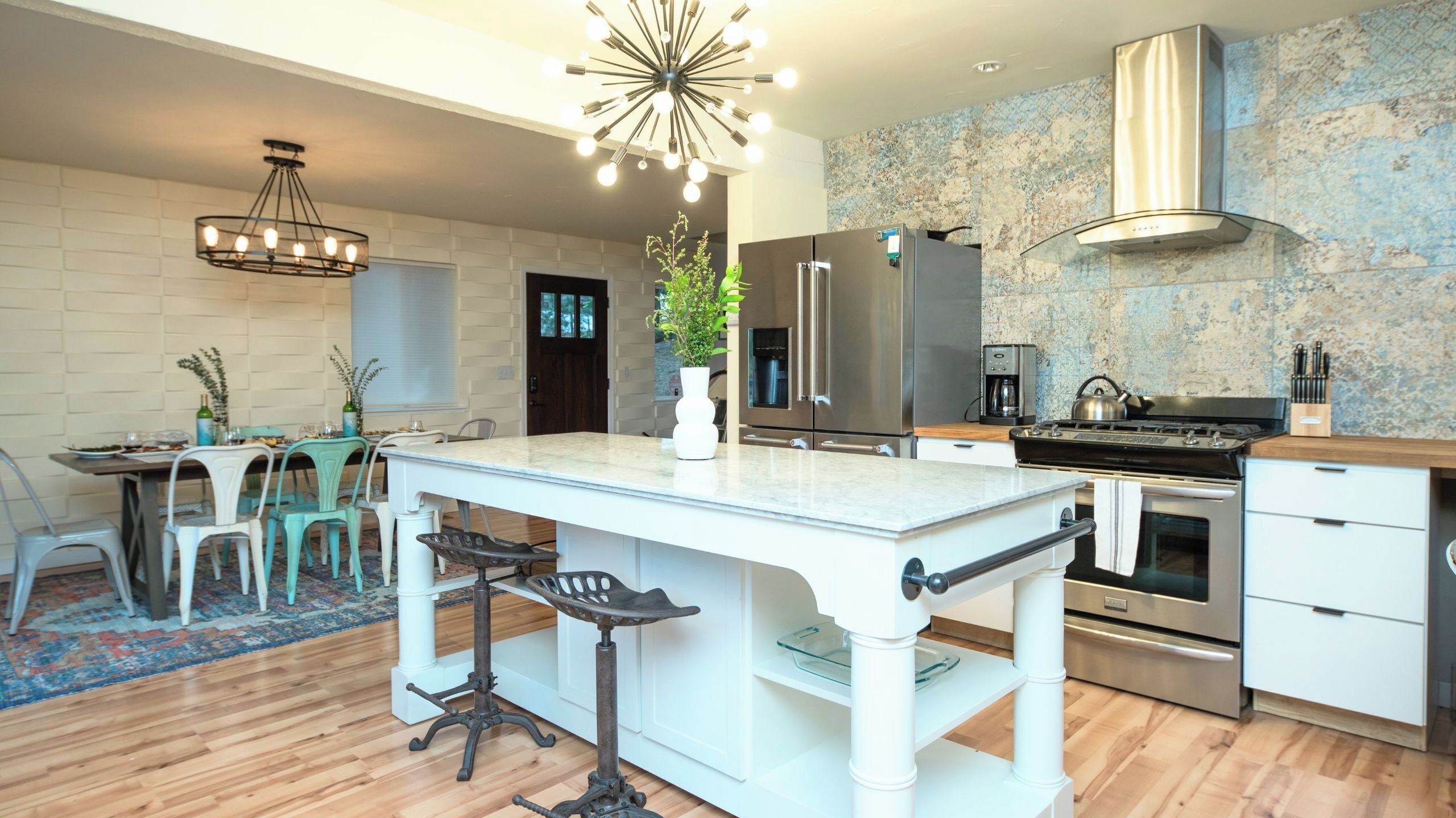A modern kitchen with a central island, stainless steel appliances, and a decorative ceiling light.