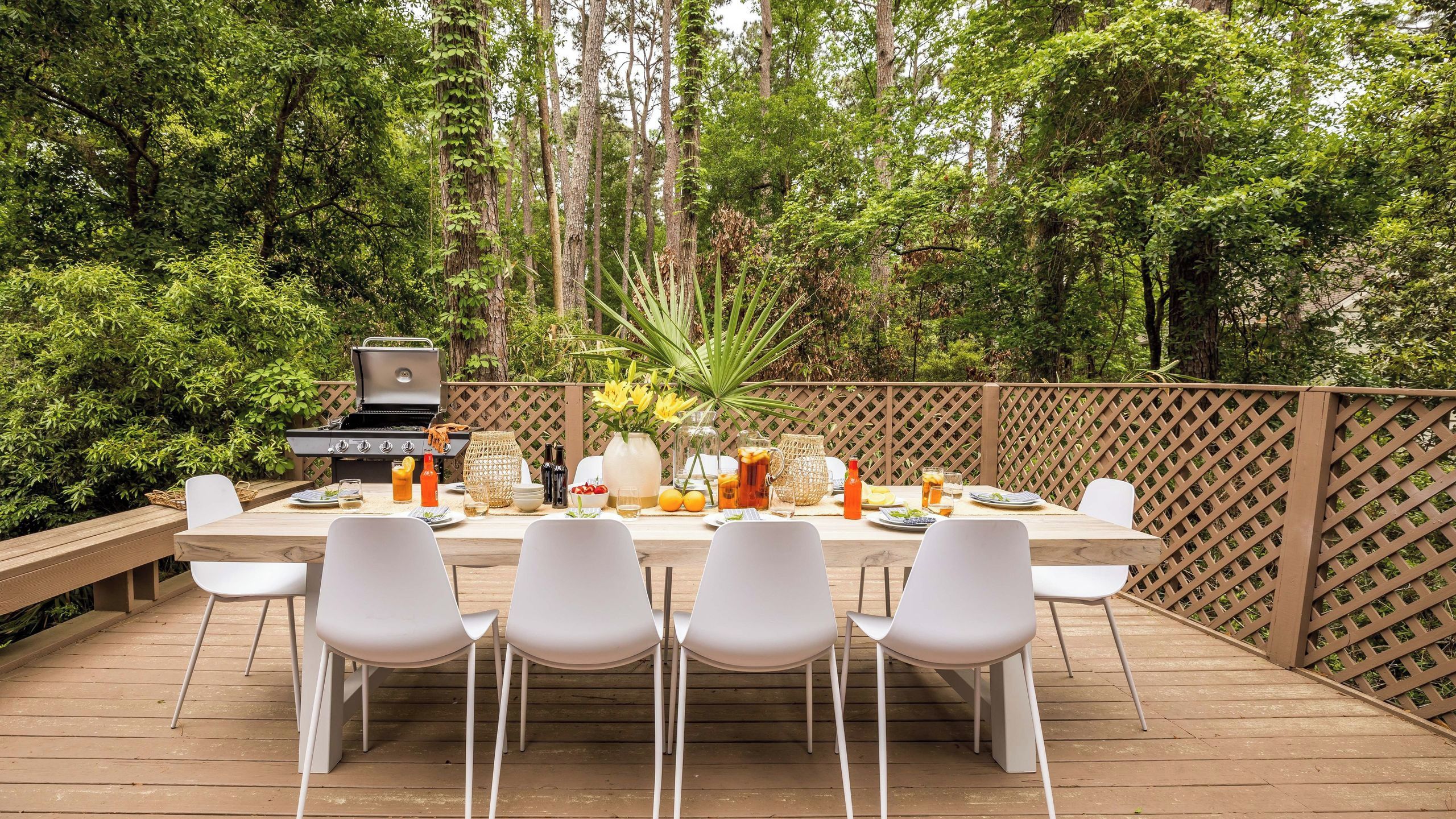 Un espace extérieur aménagé pour les repas, avec une terrasse en bois, un barbecue et une table pour quatre personnes.