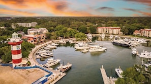 A marina with multiple boats docked, a lighthouse, and surrounding buildings.