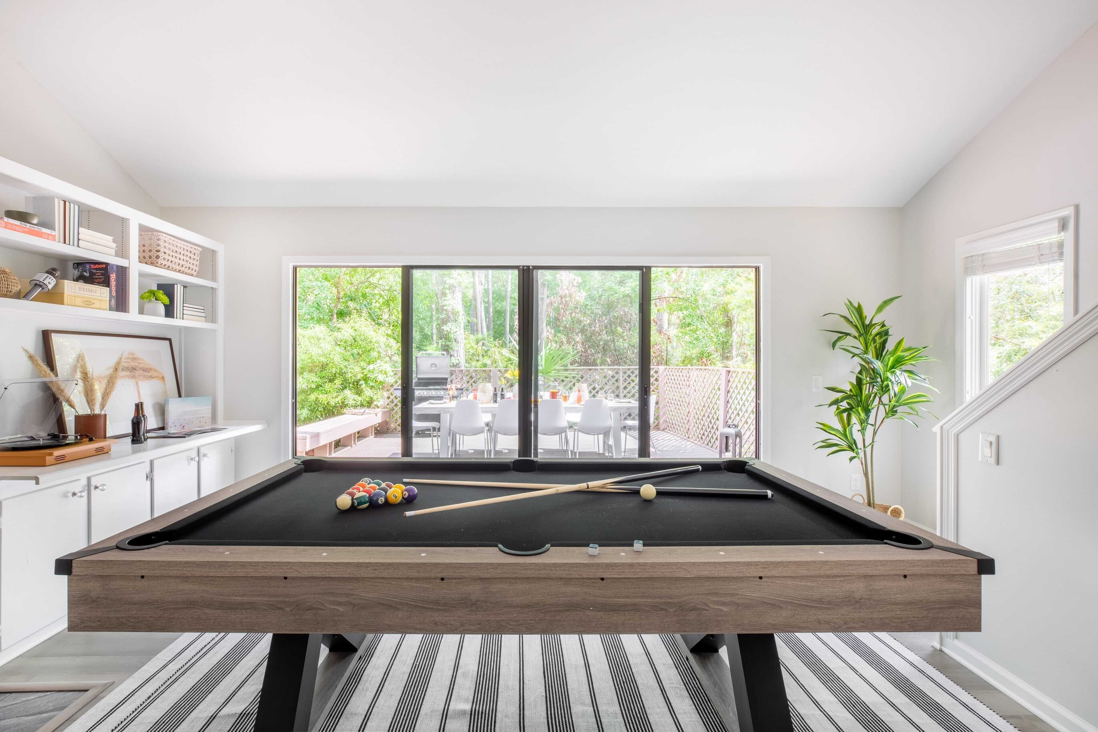 A pool table in a room with a view of an outdoor patio.