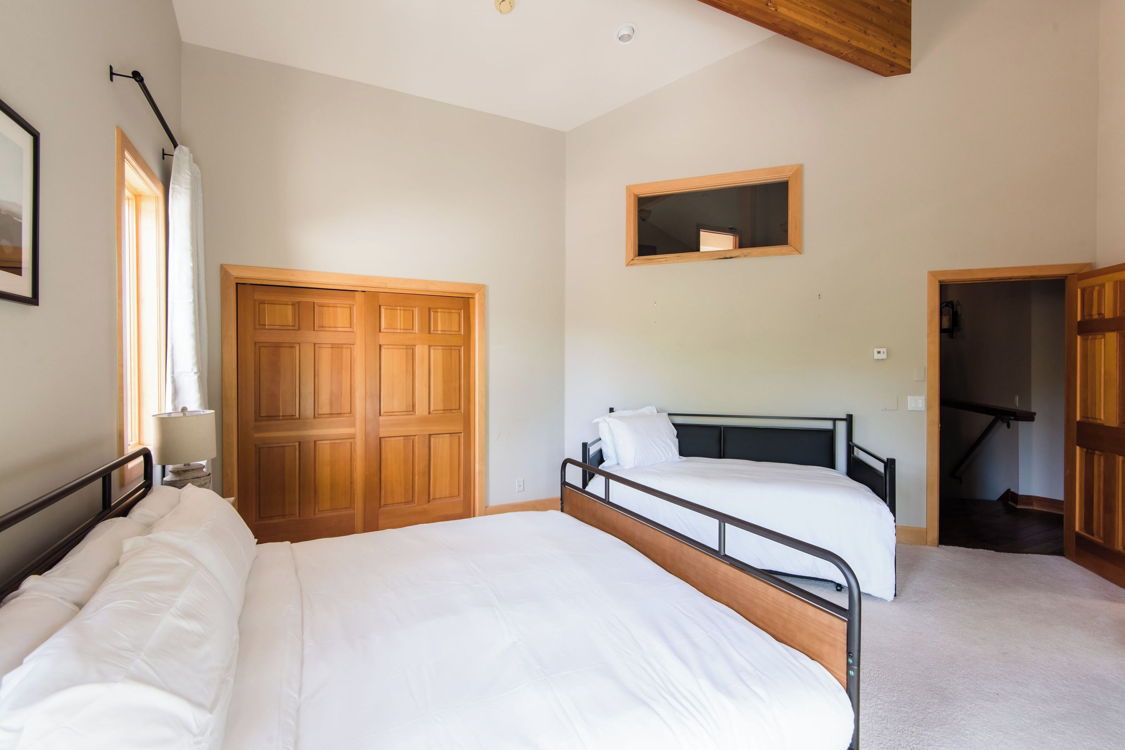 Un dormitorio con dos camas, un armario de madera y una ventana pequeña.