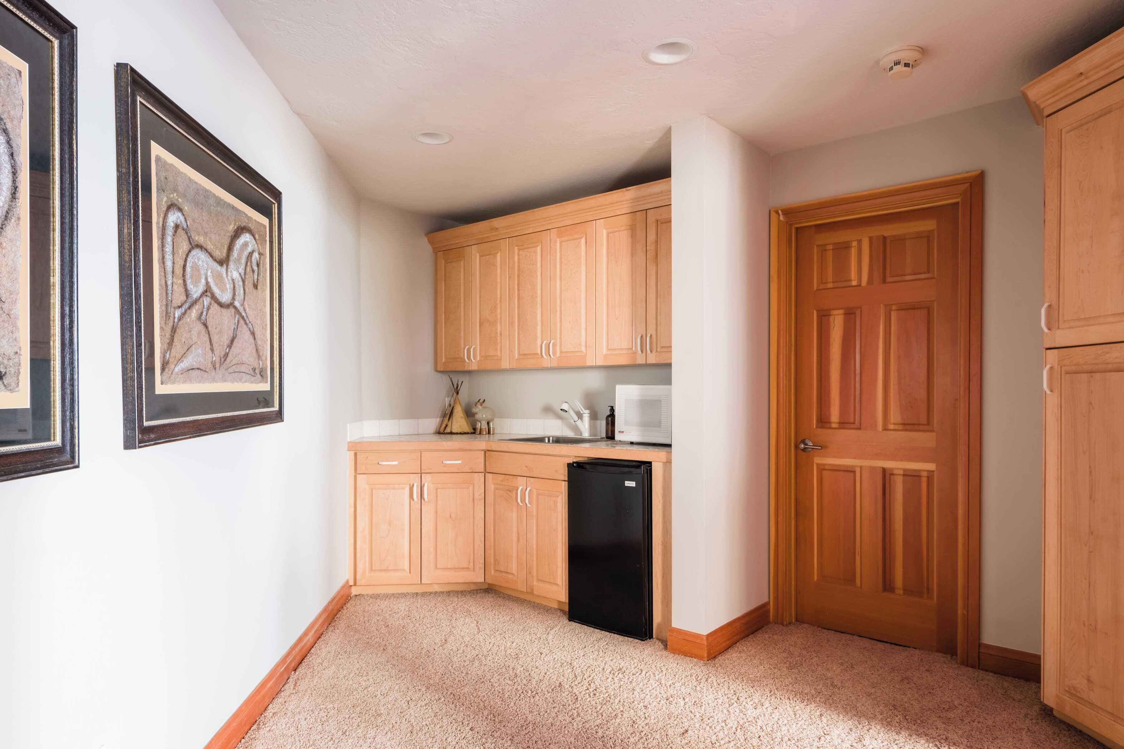 A kitchen with wooden cabinets, a black refrigerator, and a microwave.