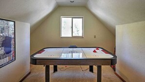 Una habitación con mesa de juego de discos, una ventana con vista a árboles y un cuadro en la pared.