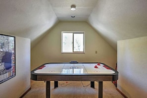 A room with a foosball table, a window, and a framed picture on the wall.