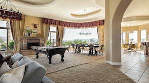A spacious living room with a pool table, a fireplace, and a dining area with chairs and a table. - Sangiovese By Avantstay Spectacular Estate w/ Pool, Hot Tub & Putting Green (Temecula)