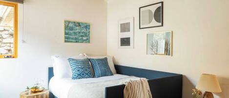 A bedroom with a bed, a nightstand, a lamp, and wall art.