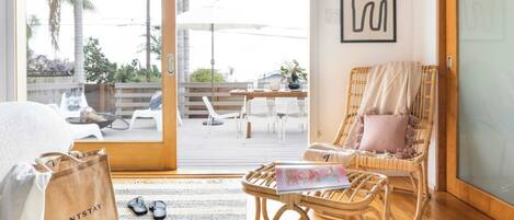 A room with a bed, a wicker chair, a table with a magazine, and a bag labeled 'AVANTSTAY'.