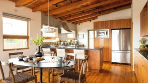 Una cocina moderna con armarios de madera, una isla central y un área de comedor con una mesa redonda y sillas.