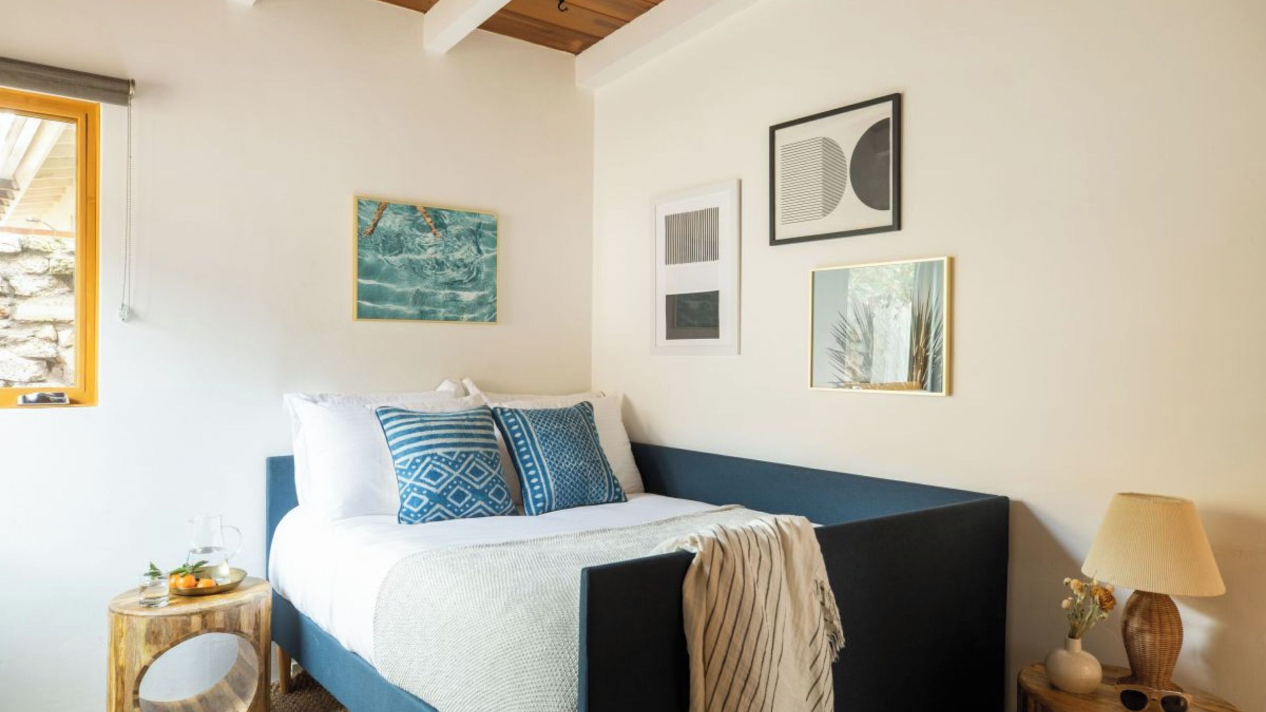 Un dormitorio con cama, mesita de noche, lámpara y decoración en la pared.