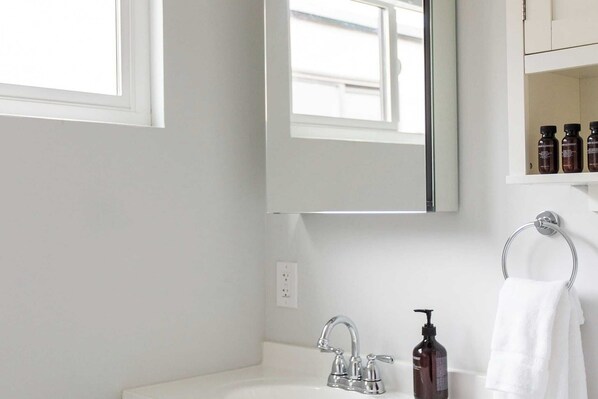 A bathroom with a white sink, a mirror, and a towel rack.