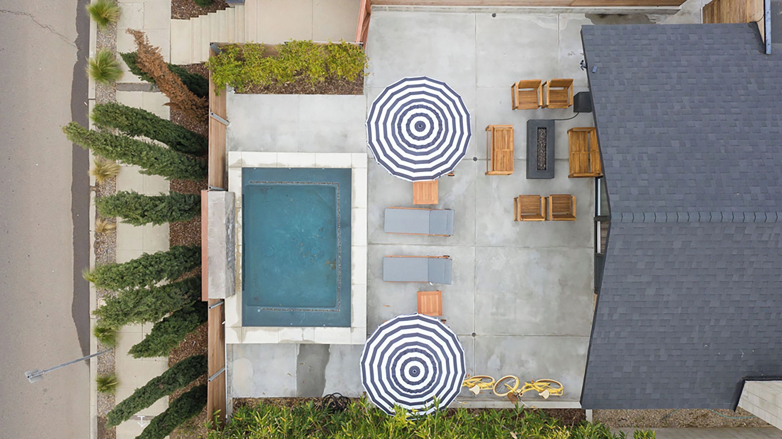 Um terraço no telhado com piscina, duas guarda-sóis e mobiliário de exterior.
