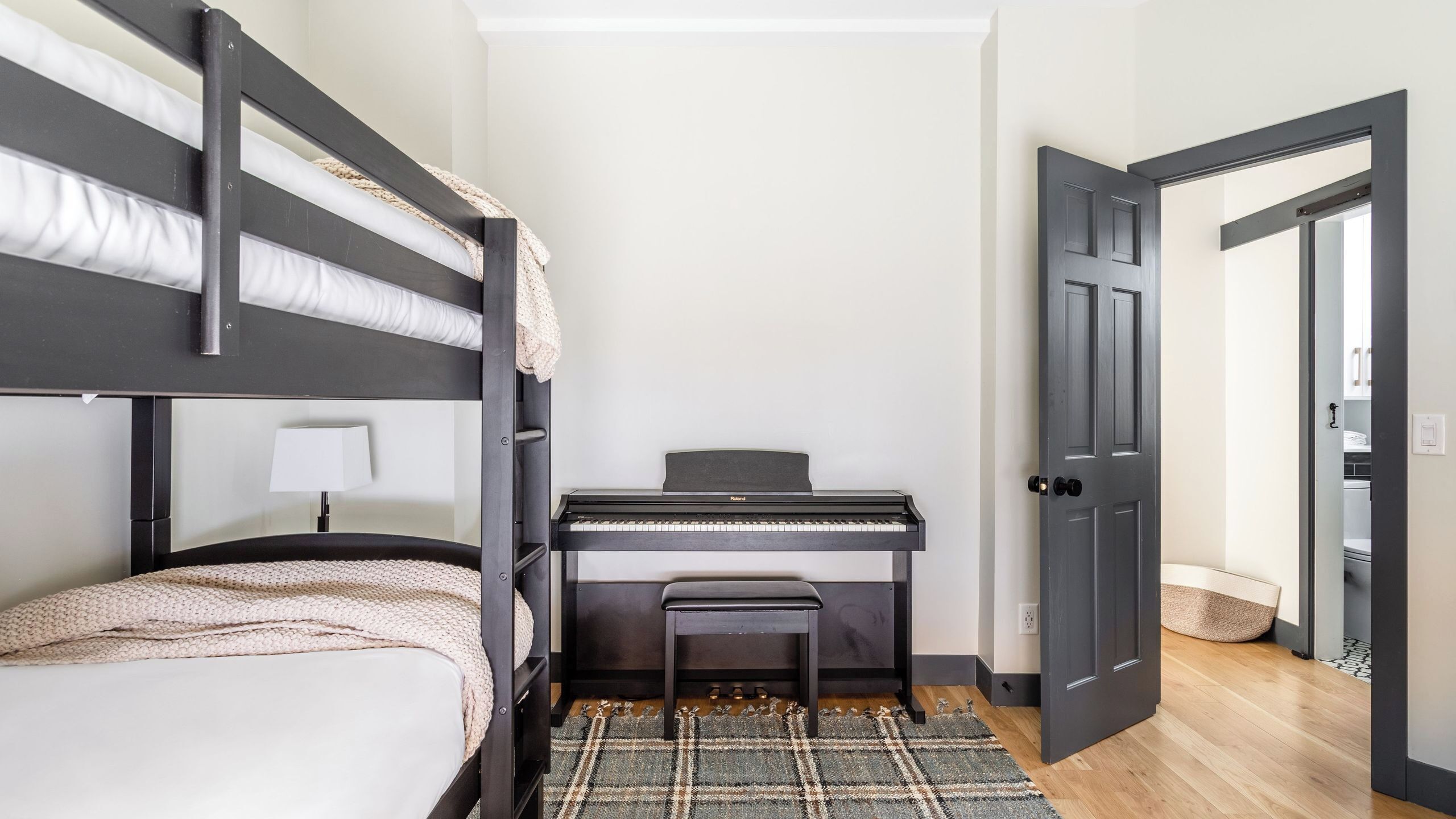 Een stapelbed, een piano, een bureau en een deur in een kamer.