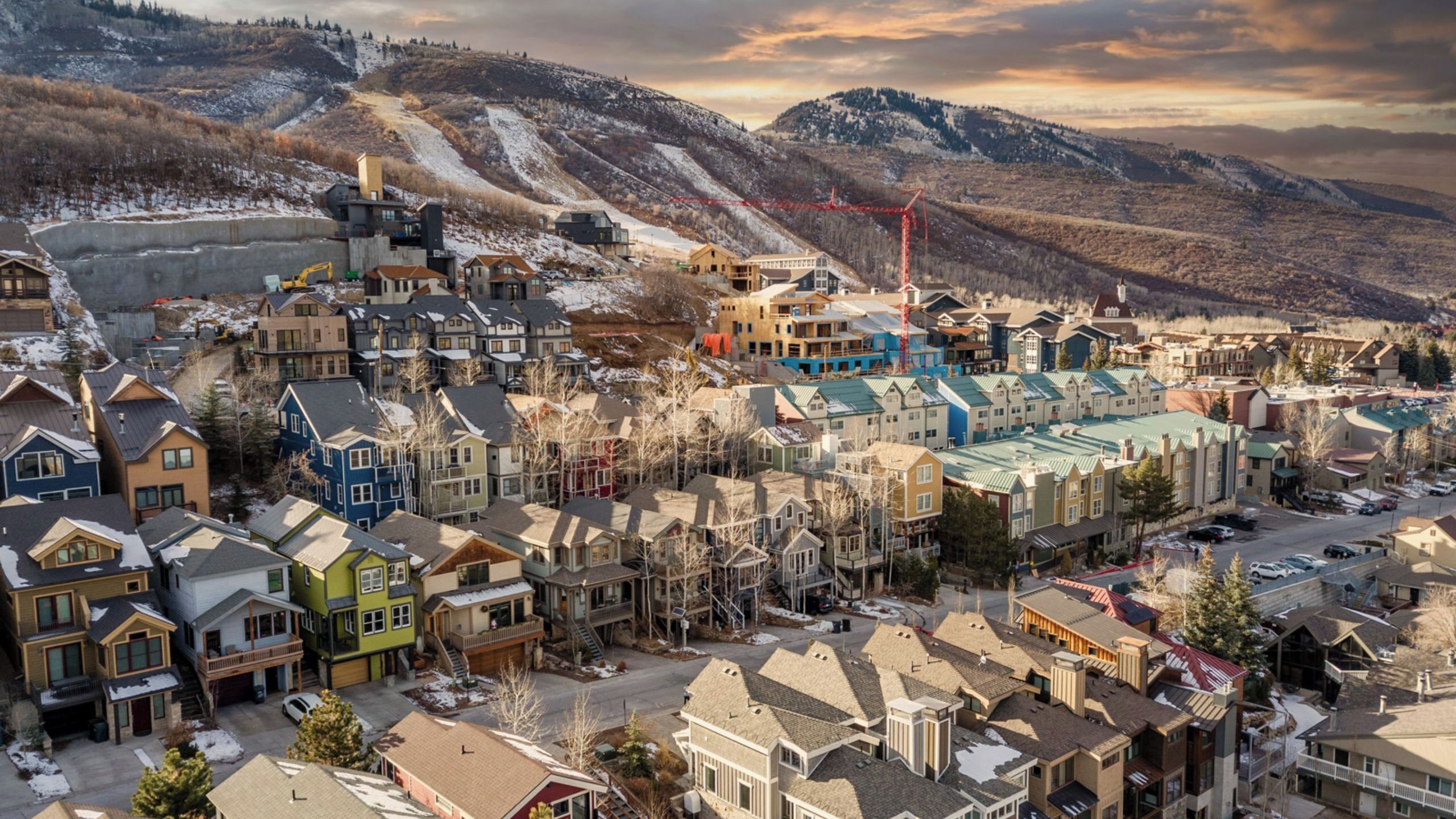 Un quartier résidentiel avec des maisons, un chantier de construction et des montagnes en arrière-plan.