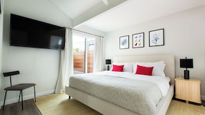 Quarto com uma cama, televisão, cadeira e obras de arte na parede.