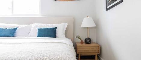 Un dormitorio con cama, mesita de noche, lámpara, un monopatín en la pared y ventana.