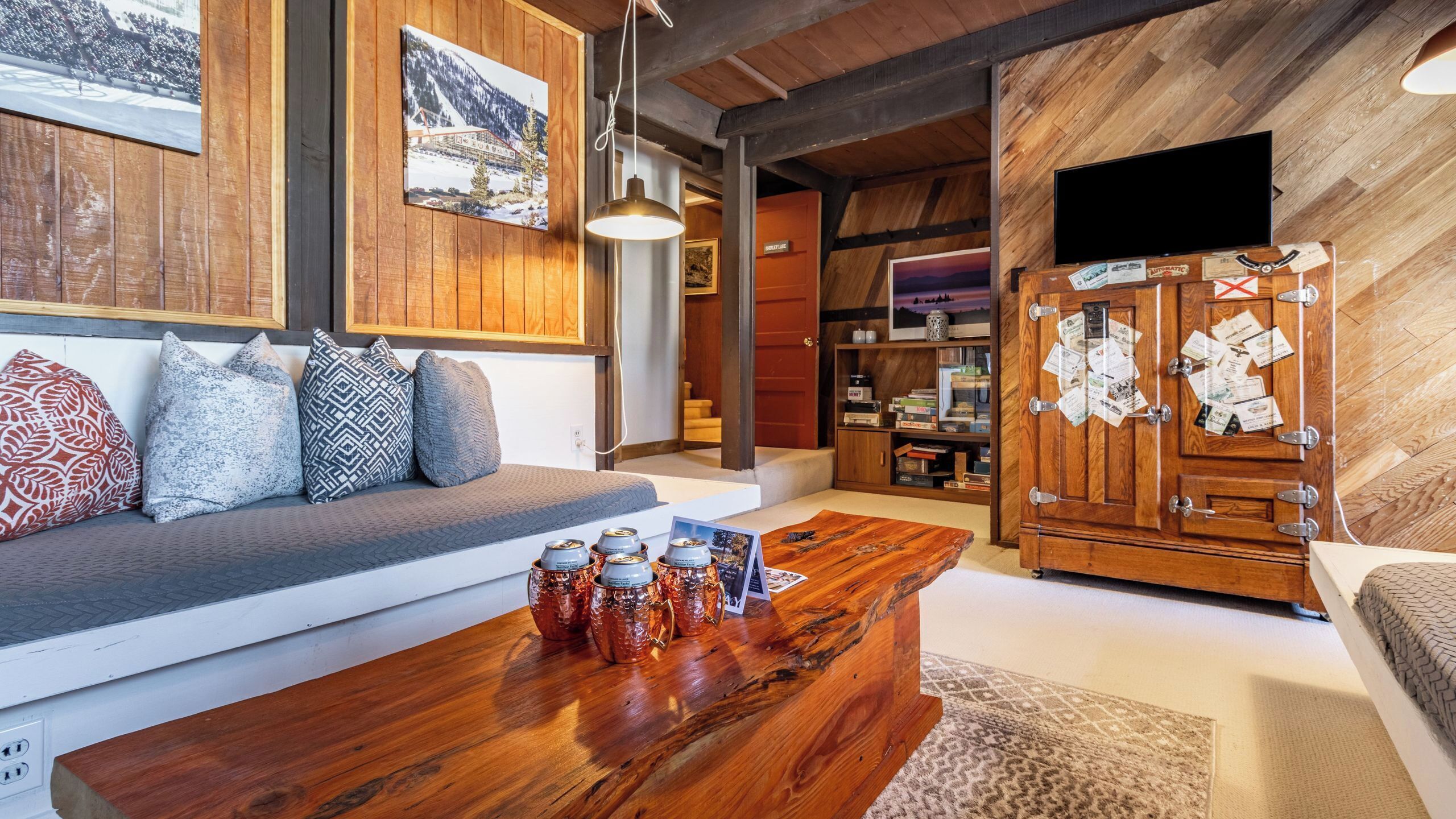 Ein gemütliches Wohnzimmer mit Couch, Fernseher, Holzschrank mit Papieren und Couchtisch.