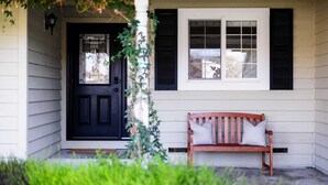 A front porch with a black door, a bench with cushions, and a window with shutters. - Cabernet By Avantstay Tranquil Sonoma Valley Oasis w/ Pool & Fire Pit (Santa Rosa)