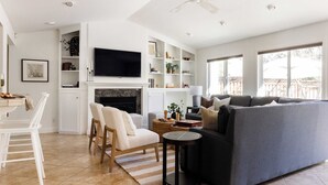 A modern living room with a fireplace, a sofa, a TV, and a dining area. - Cabernet By Avantstay Tranquil Sonoma Valley Oasis w/ Pool & Fire Pit (Santa Rosa)