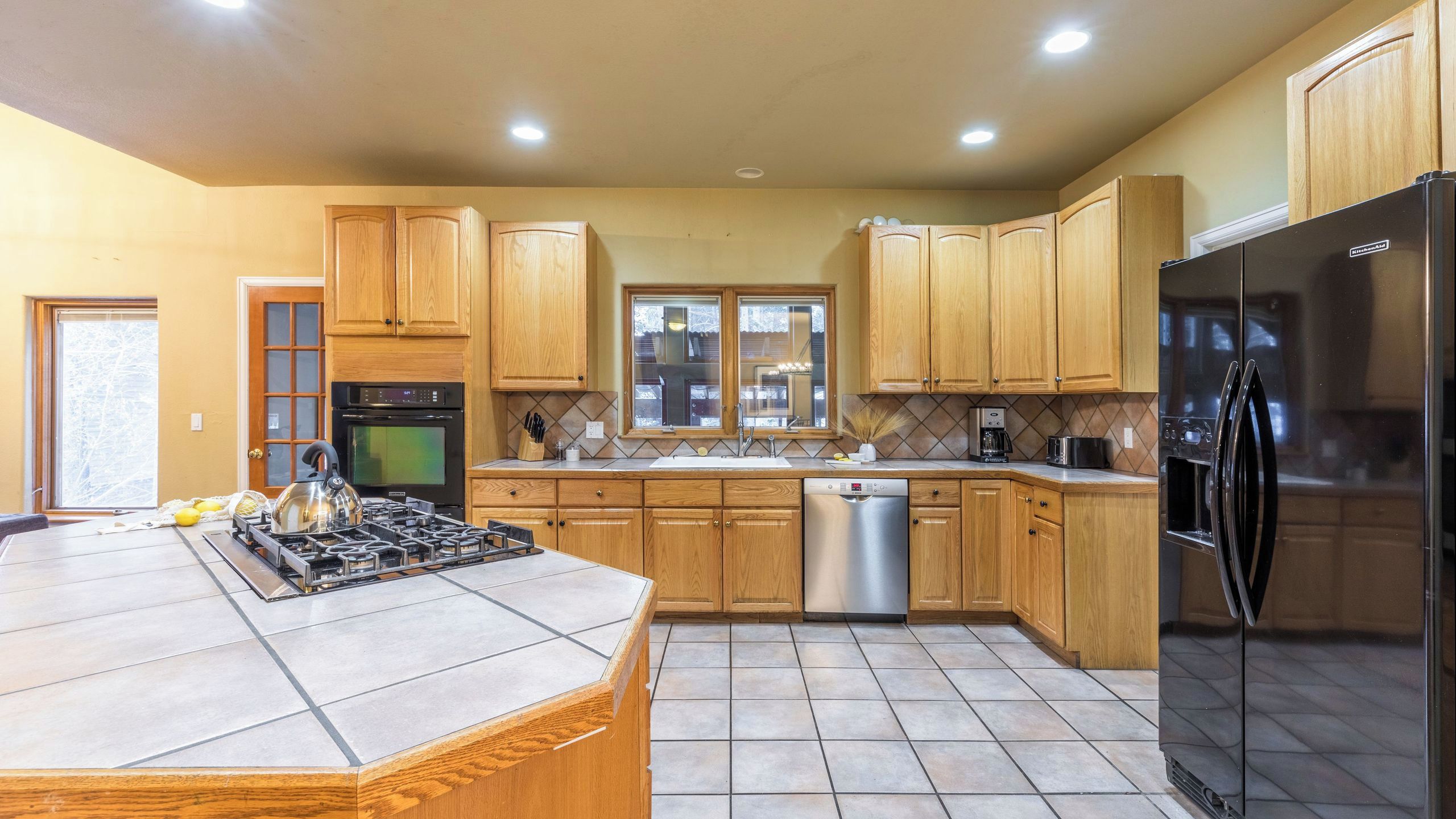 A kitchen with wooden cabinets, a stainless steel refrigerator, a gas stove, and a dishwasher.