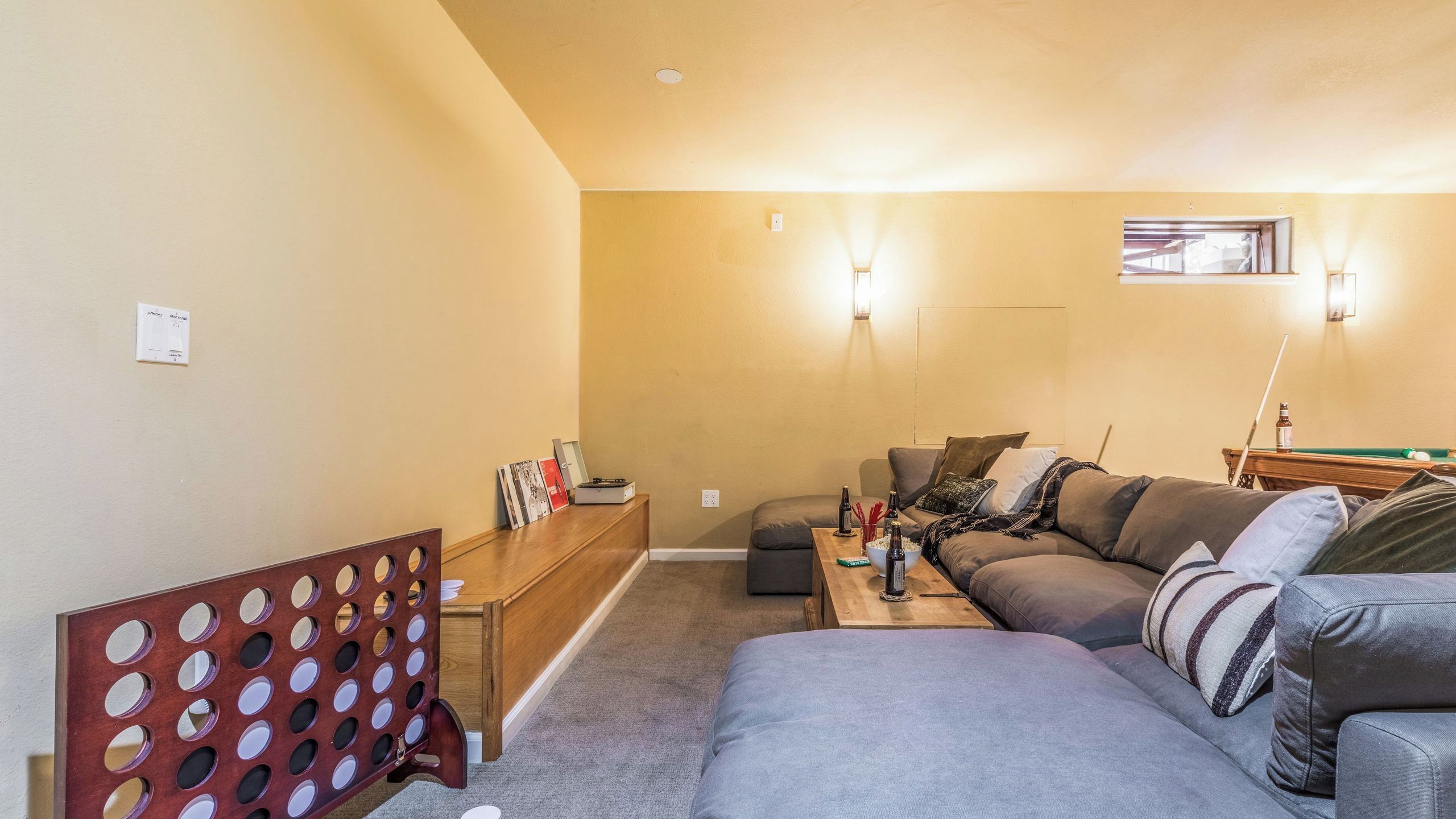 A living room with a sofa, a coffee table, and a pool table.