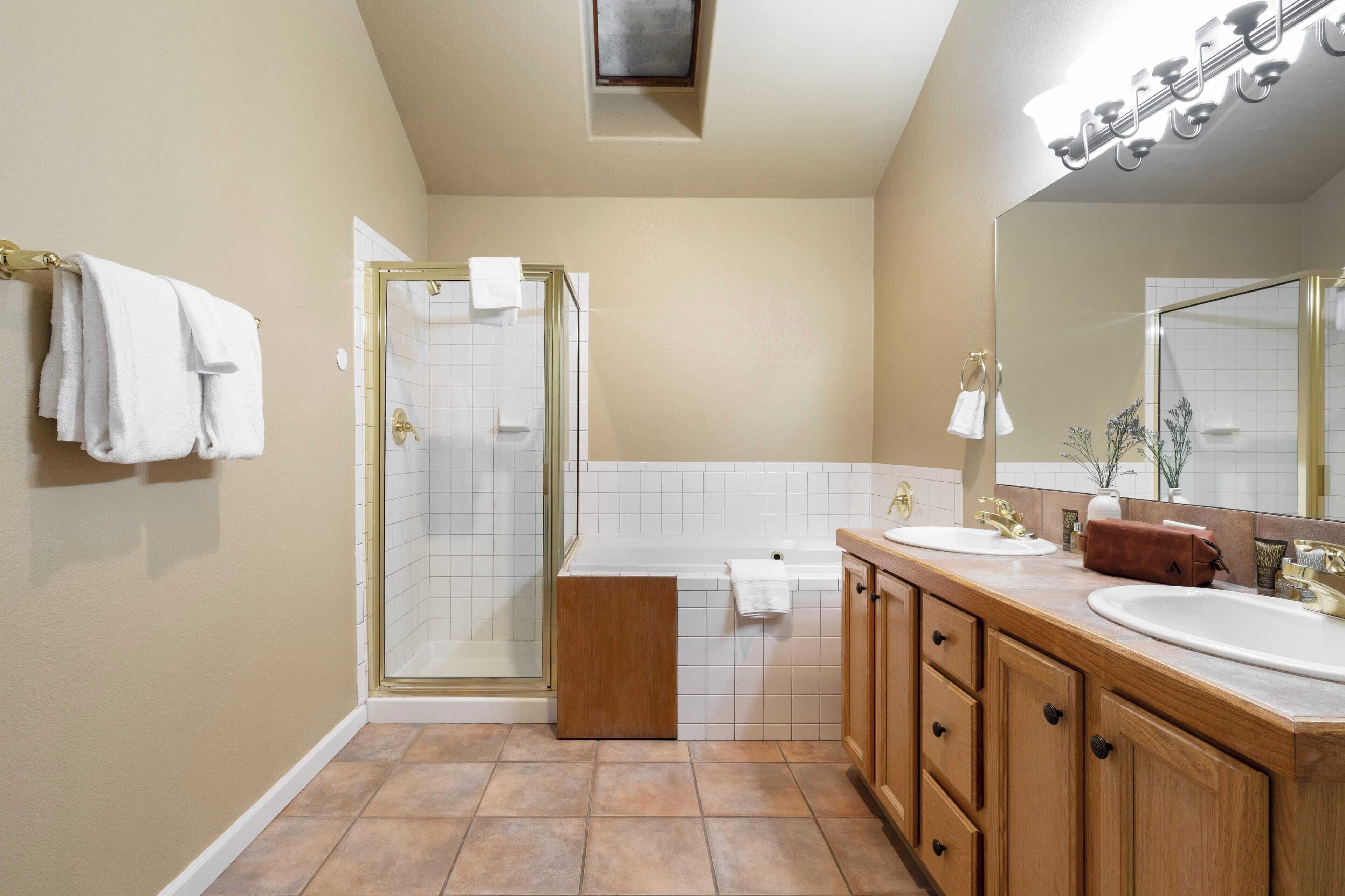Un baño moderno con cabina de ducha de vidrio, tocador doble y un espejo grande.