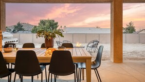 An outdoor dining area with a wooden table and black chairs, a potted plant, and a grill. - Gambel by Avantstayjtree Escape w/ Entertainers Yard, & Firepit, 3000sf (Yucca Valley)