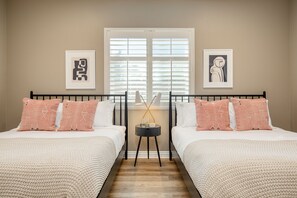 Une chambre avec deux lits, une table de chevet et des œuvres d’art accrochées aux murs.