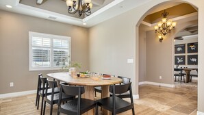 A dining area with a round table, black chairs, and a chandelier. - Gambel by Avantstayjtree Escape w/ Entertainers Yard, & Firepit, 3000sf (Yucca Valley)