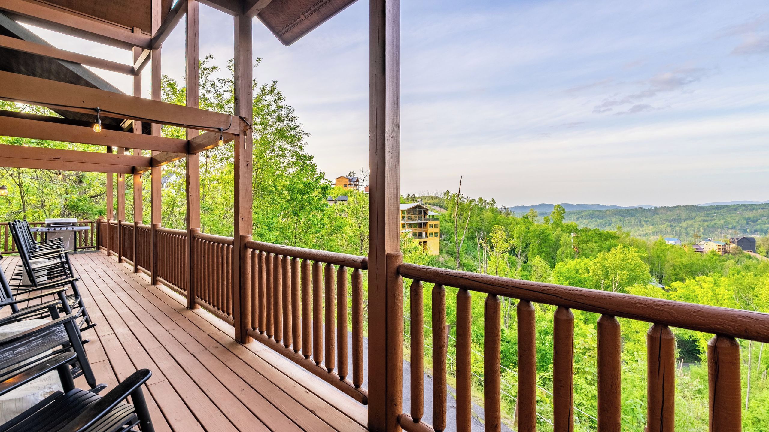 A wooden deck with outdoor seating and a view of a forested landscape.