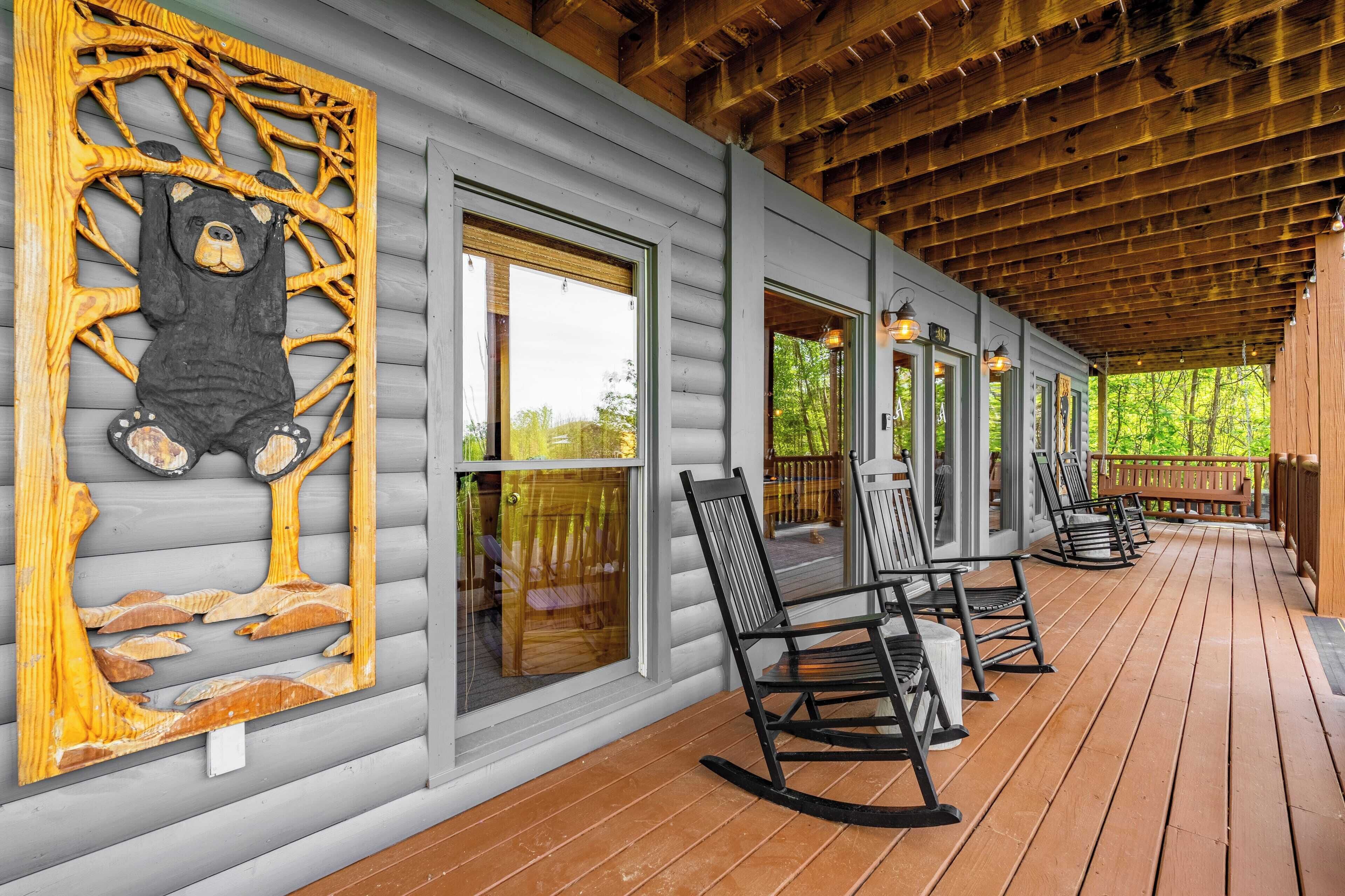 A covered porch with rocking chairs and a large bear sculpture on the wall.