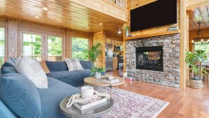 A spacious living area with a blue sofa, a stone fireplace, and a kitchen in the background.