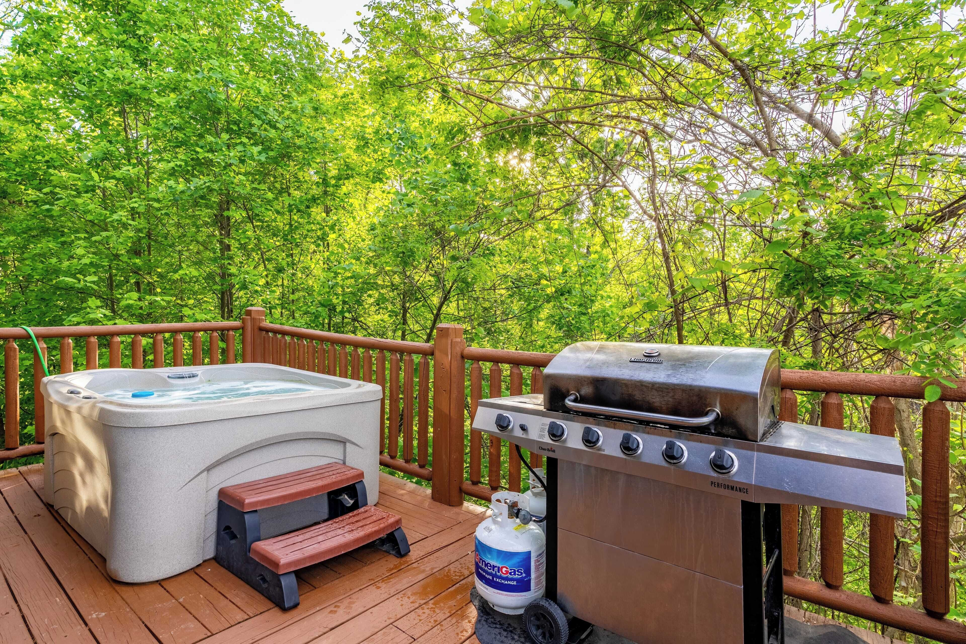 A deck with a hot tub, grill, and propane tank.