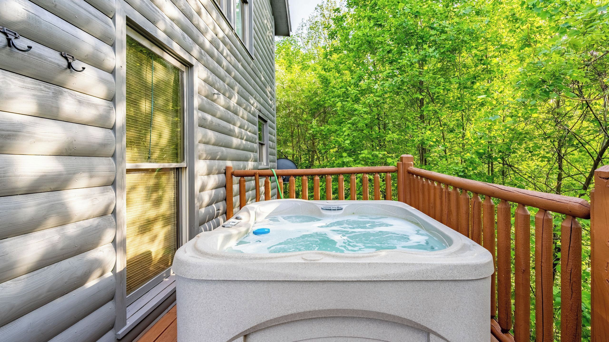 Ein Whirlpool auf einer Holzterrasse mit Blick auf einen Wald.