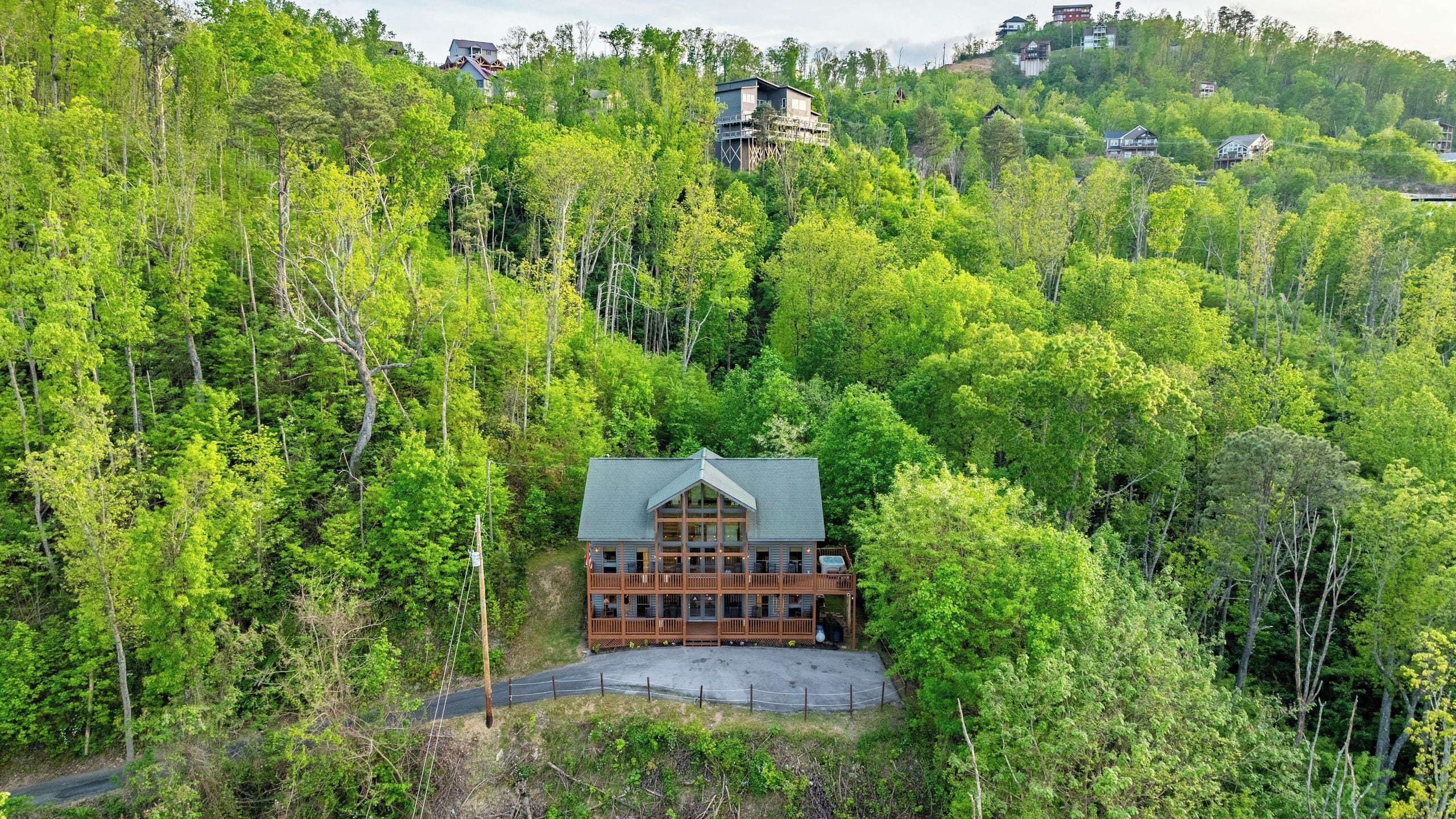 A cabin with a large porch, surrounded by dense forest.