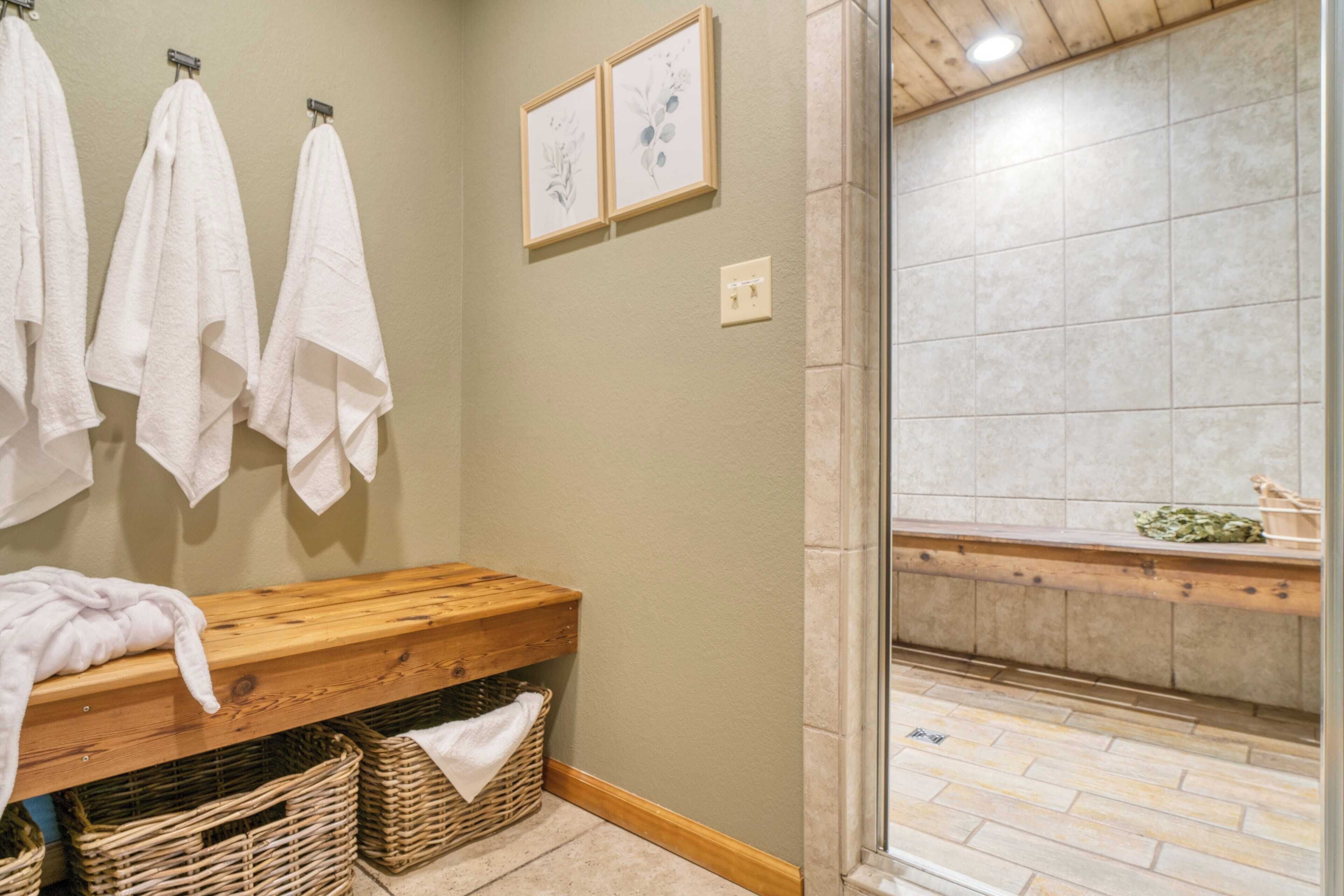 A bathroom with a wooden bench, a wall-mounted towel rack, and a shower area with a tiled floor.