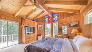 A wooden cabin bedroom with a bed, a TV, and large windows. - Mahogany by Avantstay Snowbird Cabin w/ Full Chamberlands Access! (Homewood)