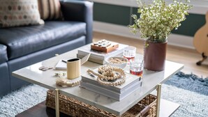 A living room with a sofa, a coffee table with books, a vase with flowers, and a guitar in the background. - Linda, Emmylou & Patsy by Avantstay 3 Unit Buyout w/ 11br in Heart of Nashville (Nashville)