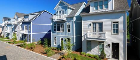 A row of townhouses with front porches, a paved driveway, and a well-maintained lawn.