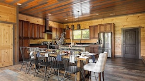 Une cuisine spacieuse avec des meubles en bois, un grand îlot central doté de sièges et un réfrigérateur en acier inoxydable.