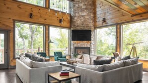 Un salón amplio con chimenea de piedra, ventanas grandes y un rincón de estar acogedor.