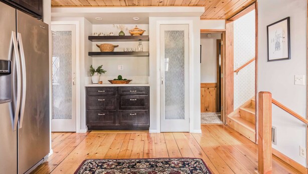 A kitchen with wooden flooring, dark cabinets, and a stainless steel refrigerator. - Walk to the Lake, Sand Volleyball Court, Pool Table, Deck Gambler by Avantstay (Big Bear Lake)