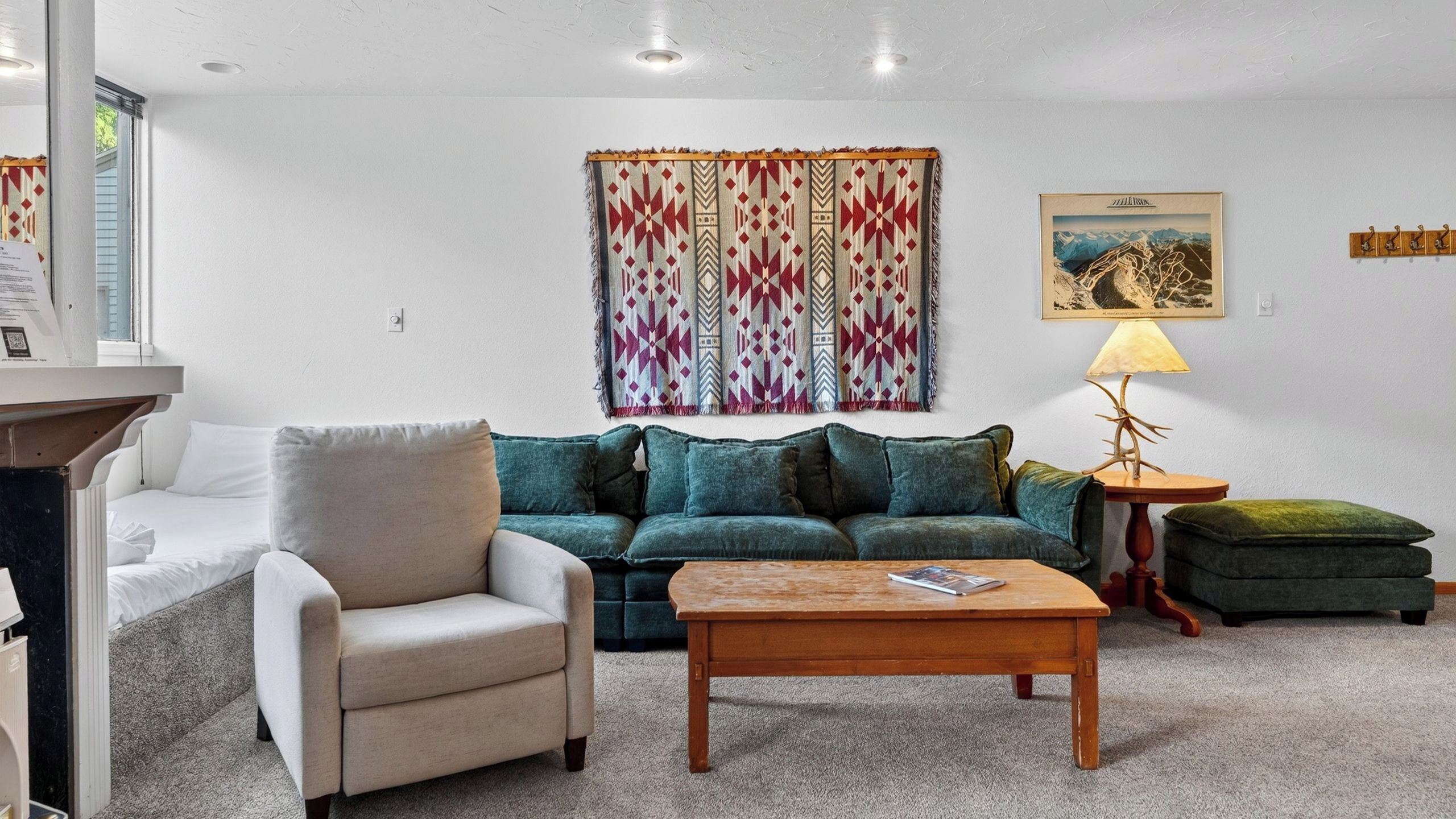 Uma sala de estar com sofá, poltrona, mesa de centro e cortina estampada.