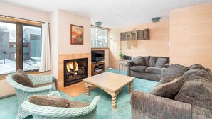 A cozy living room with wicker furniture, a fireplace, a television, and a large window. - Telluride Lodge 312 by Avantstay Close to Slopes & Town! (Telluride)