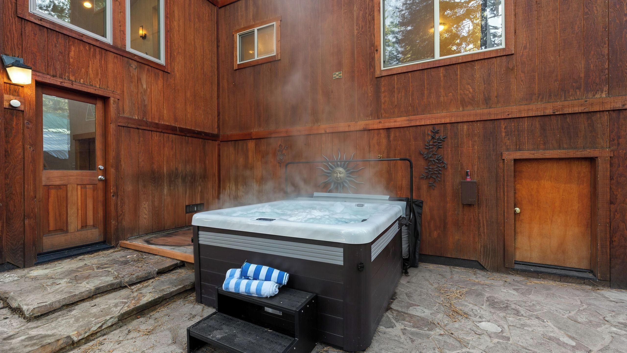 A wooden exterior with a hot tub, stone steps, and a door.