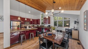 Una cocina moderna con armarios de madera, una isla central con taburetes y un comedor con mesa y sillas de madera.