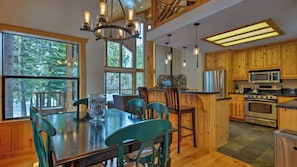 A wooden interior with a dining area, kitchen, and large windows.