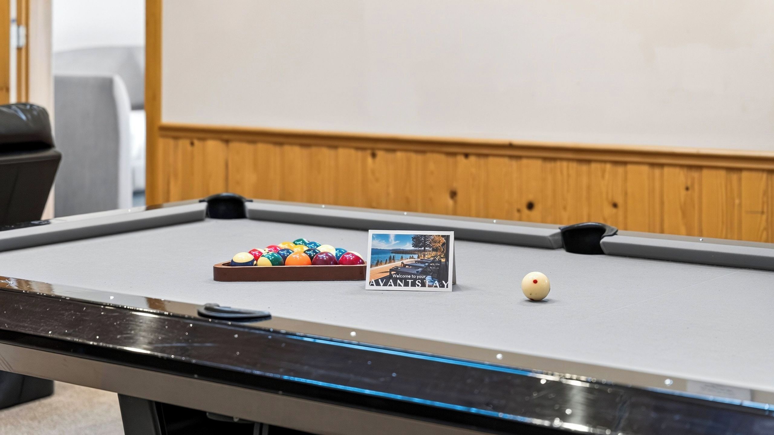 A pool table with a cue ball, a rack of billiard balls, and a welcome card.