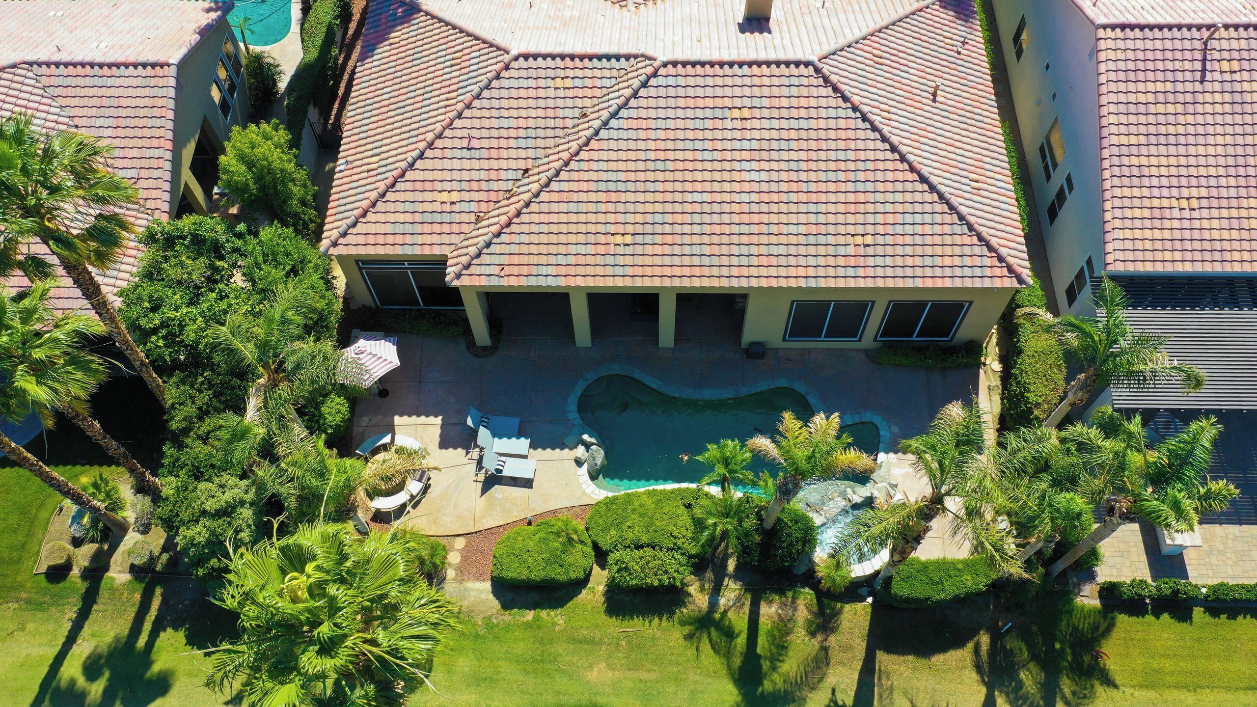 Une propriété résidentielle dotée d’une piscine, d’un patio couvert et d’un jardin bien entretenu.