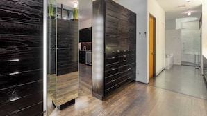 A modern interior with a wooden floor, a dark wooden cabinet, and a glass partition.
